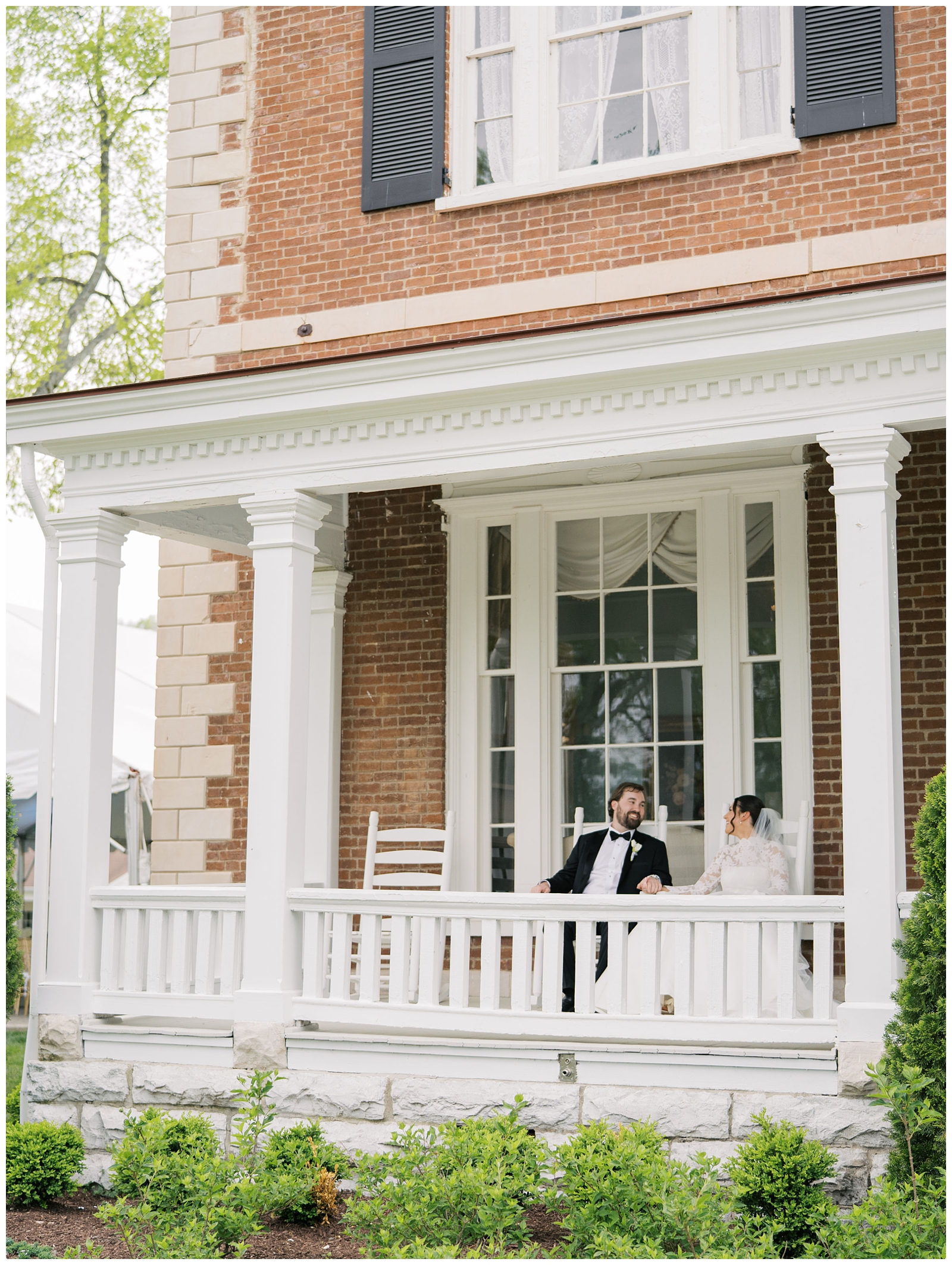 bride and groom sitting in rocking chairs on front porch at their Ravenswood Mansion Wedding